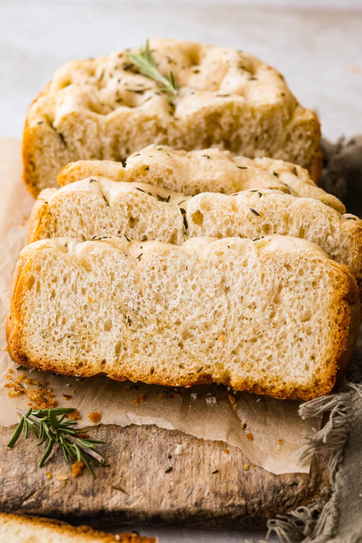 This slow cooker focaccia is the easiest way to get homemade bread on the table! Frozen dinner rolls transform into a pillowy, herb-flecked loaf with barely any effort. Just drizzle, dimple, and let your slow cooker do the rest. Sliced slow cooker focaccia bread on a cutting board.