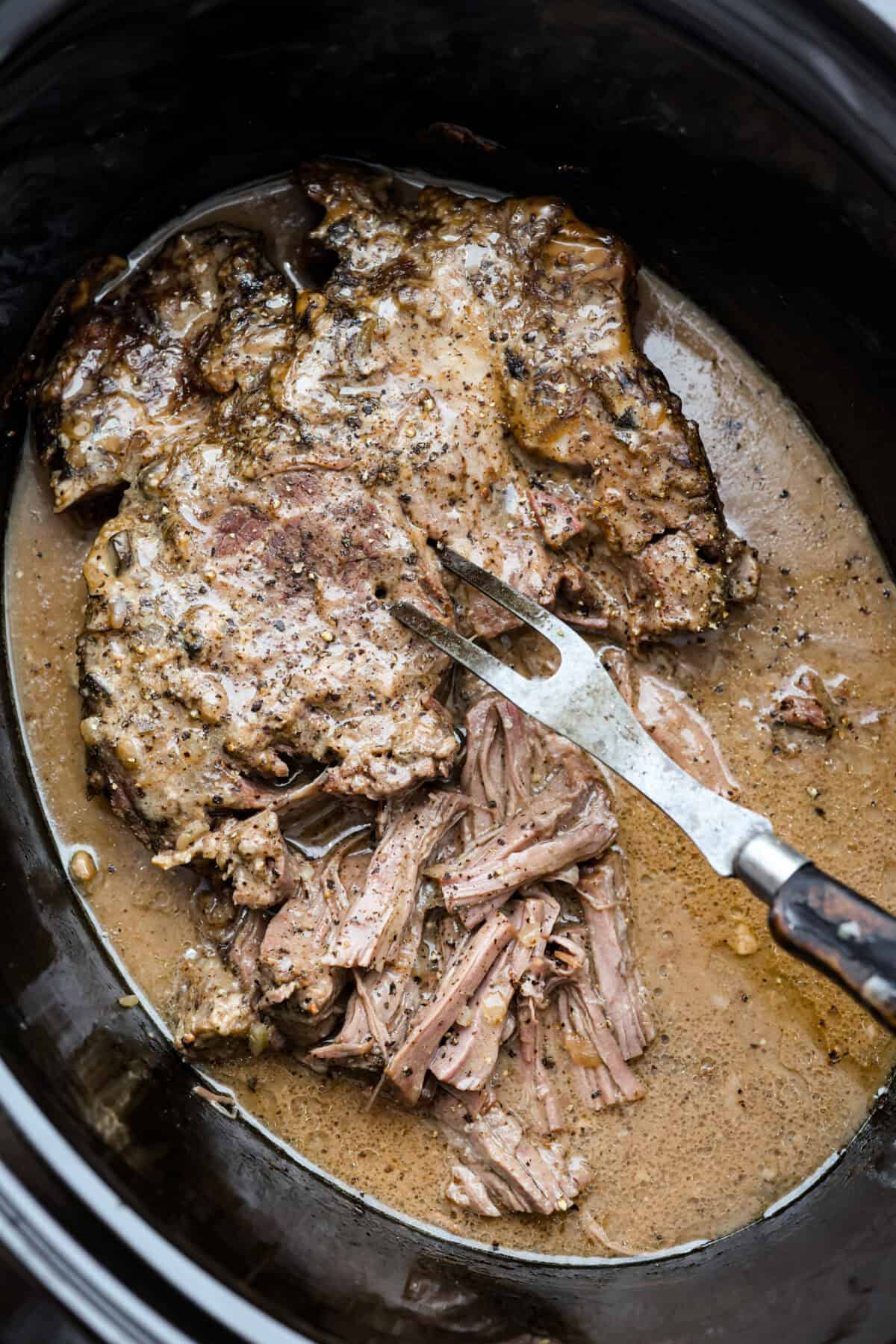 This 4 Ingredient Mushroom Beef is just like how my grandma used to make her Sunday roast, simple and cozy. You toss it all in the crockpot, and it comes out melt in your mouth tender with a rich gravy thatโs perfect over everything. Large, cooked, 4 ingredient mushroom beef in a crockpot.