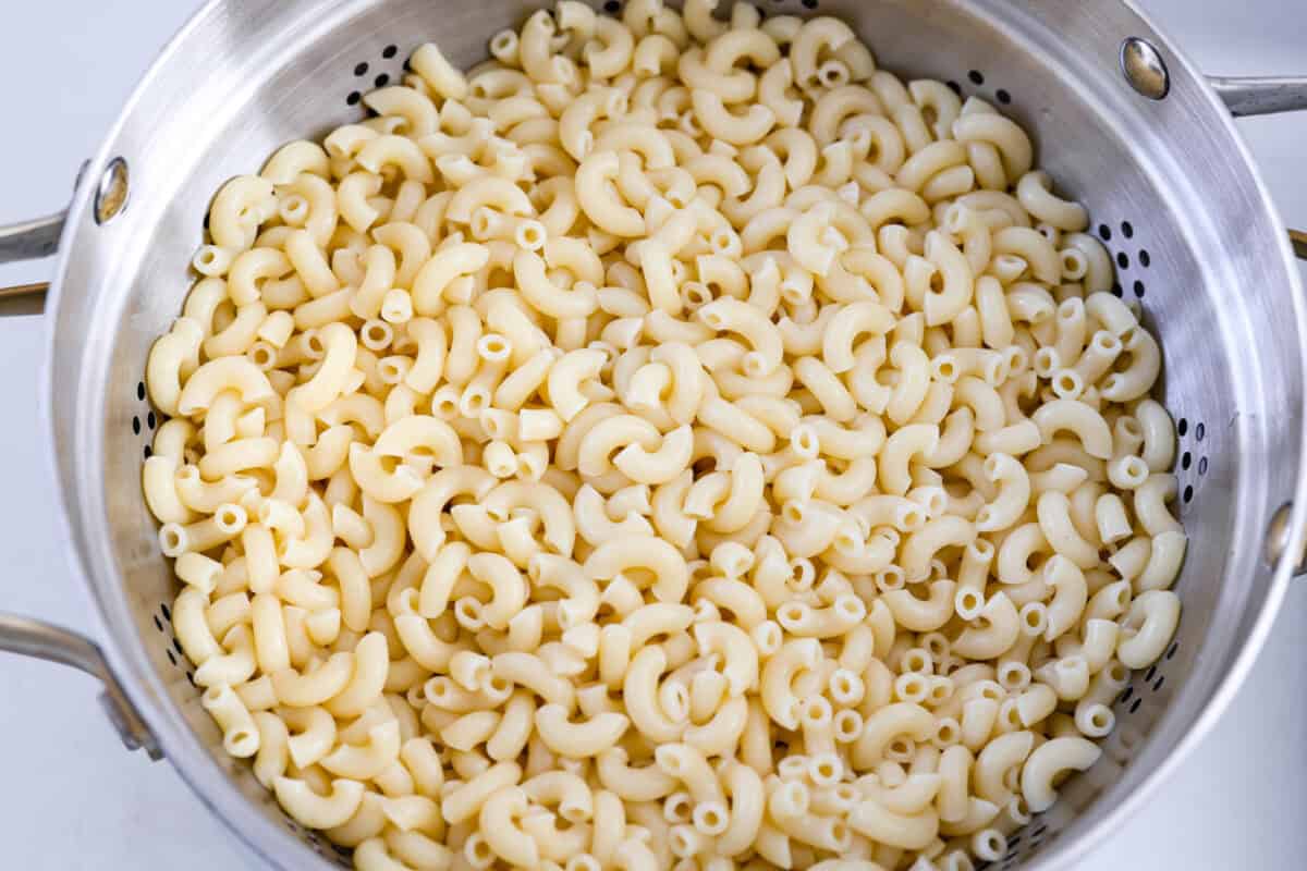 There’s something delightfully old school about Amish pasta salad. The sweet, tangy dressing, the macaroni, the chopped eggs, the crunchy celery. It tastes like the kind of recipe that’s been living in a handwritten church cookbook for decades. Colander full of cooked macaroni noodles.