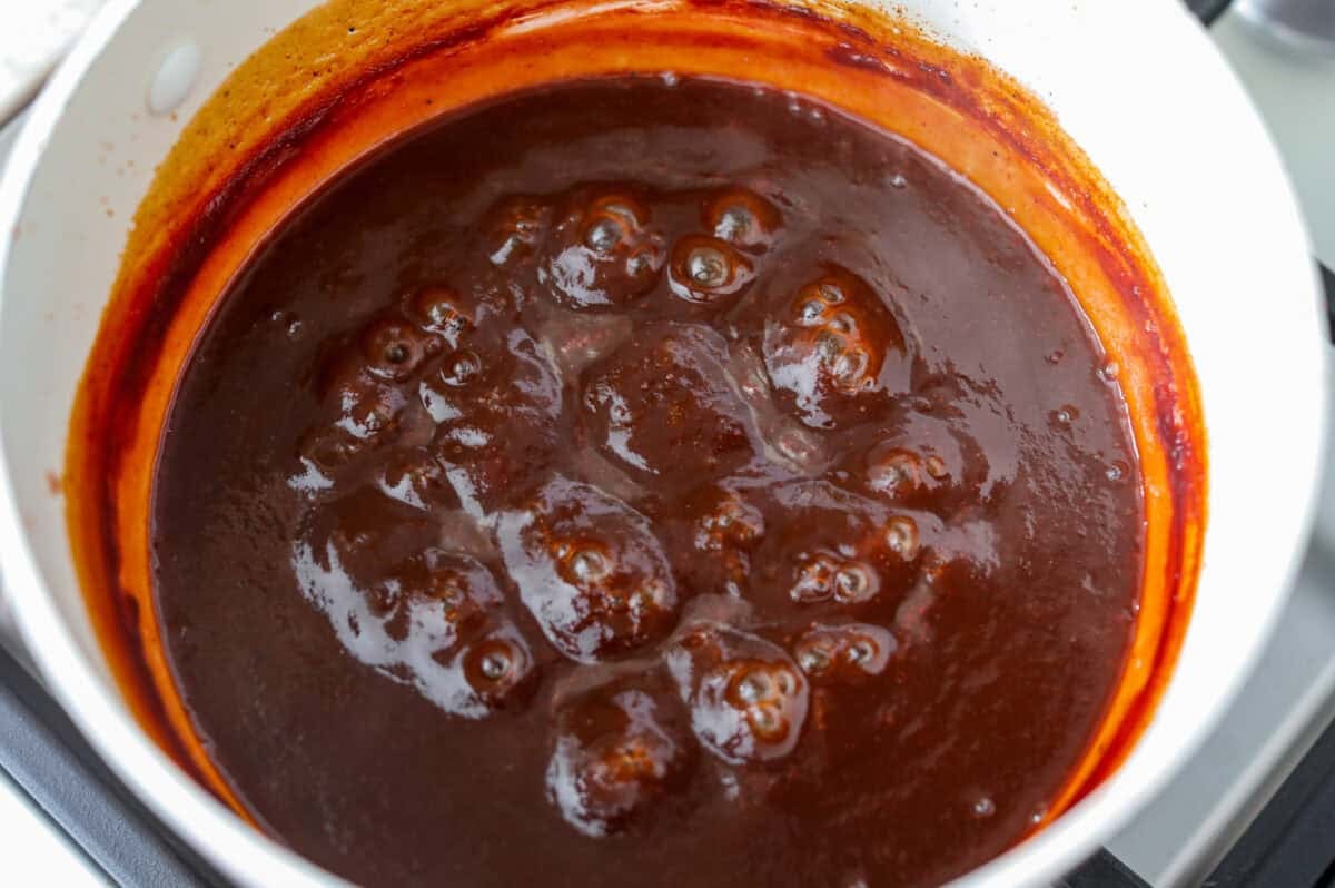 My Dr Pepper BBQ sauce is sweet, tangy, smoky, and seriously addictive! Made with simple ingredients and Dr Pepper for aย rich caramelized flavor. Itโs perfect for all your BBQ sauce needs! Sauce thickened and simmering in the pot.