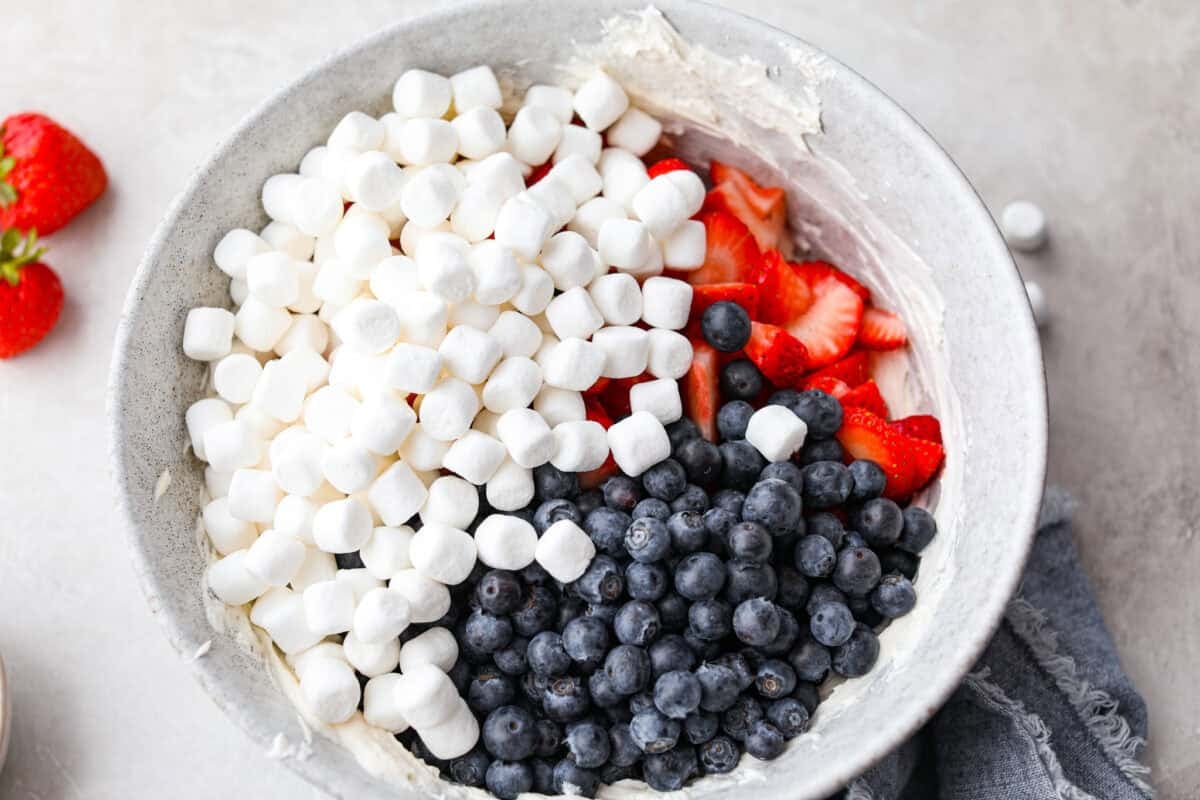 This red, white, and blue cheesecake salad is the fun summer side dish everyone goes back for. Itโs creamy, fluffy, packed with berries and marshmallows, and so easy to bring to a BBQ, potluck, or Fourth of July party. Marshmallows, and berries added to the yogurt mixture.