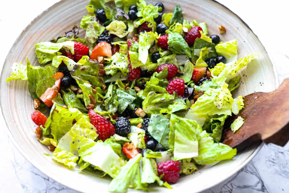 This copycat Zupa’s Nuts About Berries Salad is fresh, bright, and full of texture in every bite. Loaded with sweet berries, crunchy cinnamon almonds, crisp greens, and creamy poppyseed dressing, it tastes just like the restaurant favorite right at home! All of the salad ingredients mixed together with the dressing.