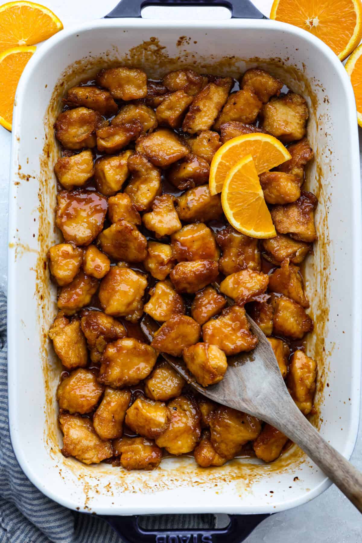 Baked orange chicken is sweet, tangy, and coated in the best sticky orange sauce. It has all the flavor of your favorite takeout, but itโs made right at home and baked until the chicken is perfectly tender. Top down shot of baked orange chicken in a 9x13 baking dish.