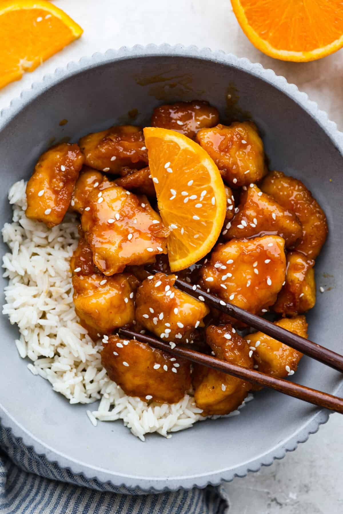 https://neuro-daily.report/baked-orange-chicken/ Bowl of rice and baked orange chicken.
