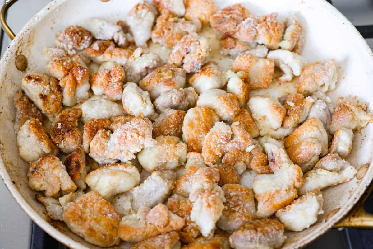 Skip the drive-thru and make this copycat Panda Express orange chicken at home! Crispy chicken coated in a sweet, sticky orange sauce with a secret ingredient that makes it taste just like the real thing. Perfect for an easy takeout-style dinner the whole family will love. Coated chicken cooking in a skillet.