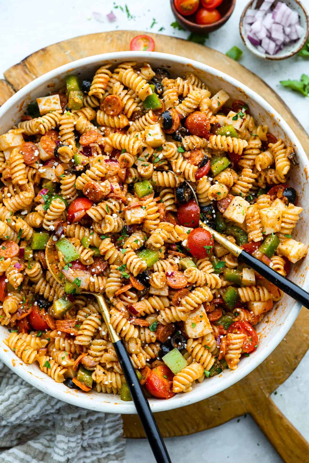 Pizza pasta salad is a fun twist on two family favorites! It's packed with pepperoni, mozzarella, fresh veggies, and a tangy pizza-inspired dressing. Get out of your pasta salad rut and make this unique and incredibly flavorful recipe! Large serving bowl of pizza pasta salad.