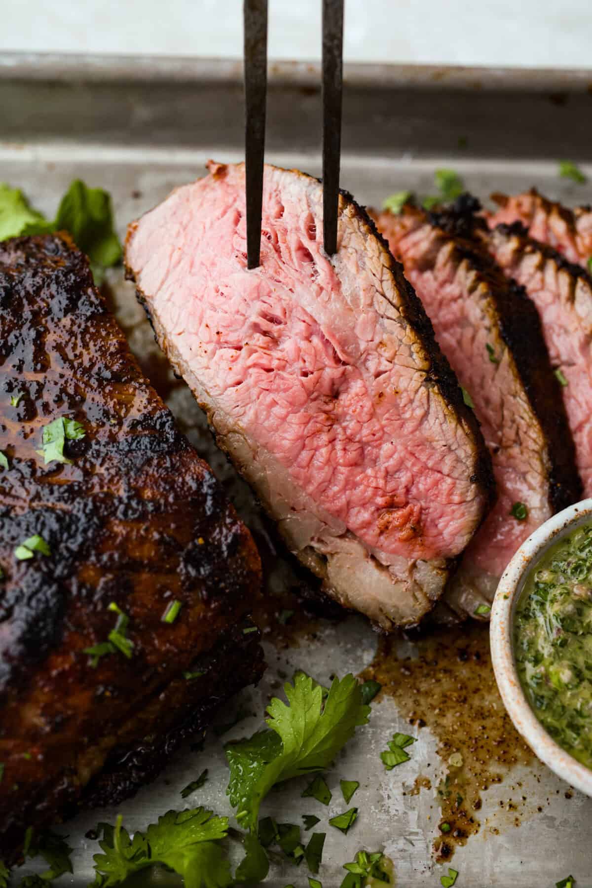 Santa Maria grilled tri-tip is juicy, smoky, and loaded with bold flavor from a delicious spice rub. Grilled until perfectly tender with a gorgeous crust, itโs an easy recipe thatโs always a hit at cookouts and summer dinners. Close up of a slice of Santa Maria Tri-Tip.