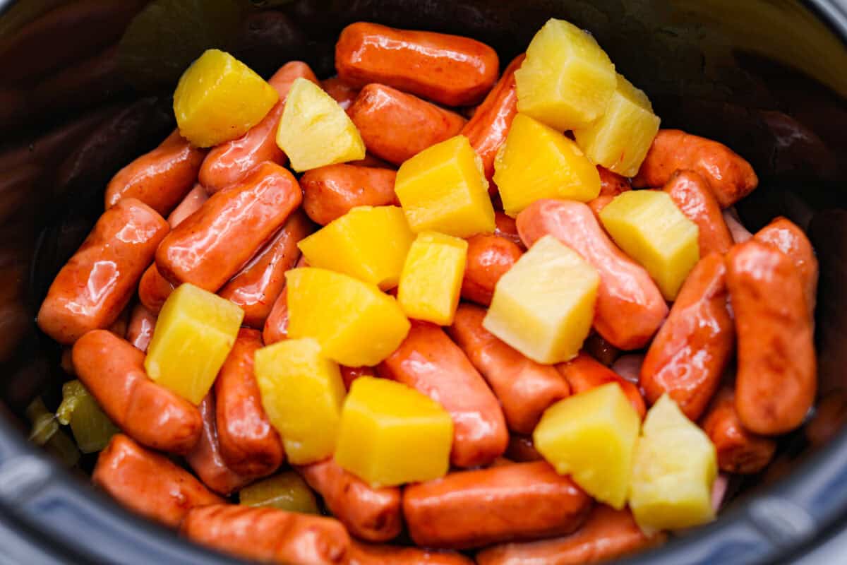 Don't be surprised if these Hawaiian Lil' Smokies steal the show! Slow cooked in a sweet and tangy pineapple BBQ sauce, they're bite-sized, irresistible, and dangerously easy to snack on. Pineapple and lit'l smokies in a slow cooker.