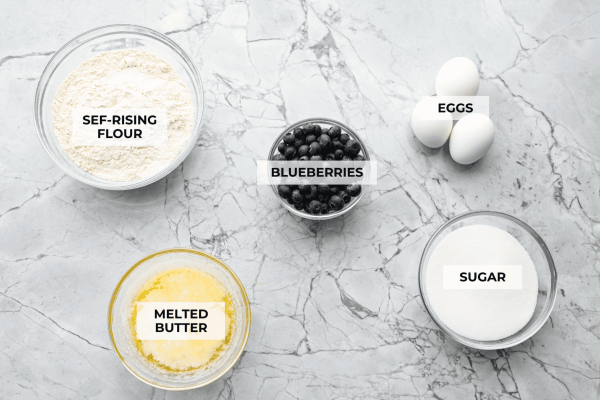 This 5 Ingredient Blueberry Bread is the little shortcut loaf youโll make once and then suddenly need every weekend. Itโs soft, sweet, full of juicy blueberries, and comes together with only five simple ingredients. Overhead shot of labeled ingredients.