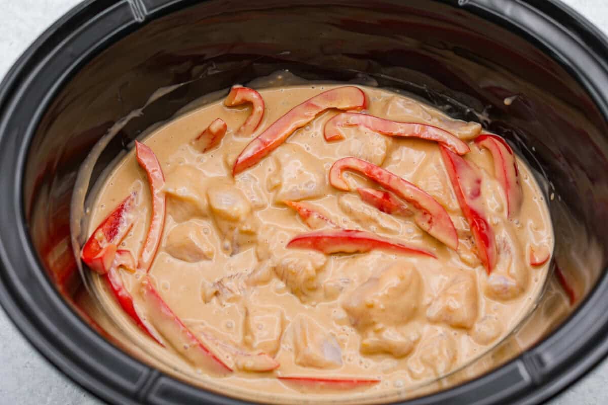 You asked, I listened! This slow cooker Thai peanut chicken got a serious glow-up! The sauce is creamy, savory, a little sweet, and packed with peanut coconut flavor. Iโd drink it with a straw if that were socially acceptable, but spooning it over rice, noodles or adding it to lettuce wraps is probably the better dinner move. Sauce added to the peppers and chicken in the slow cooker.