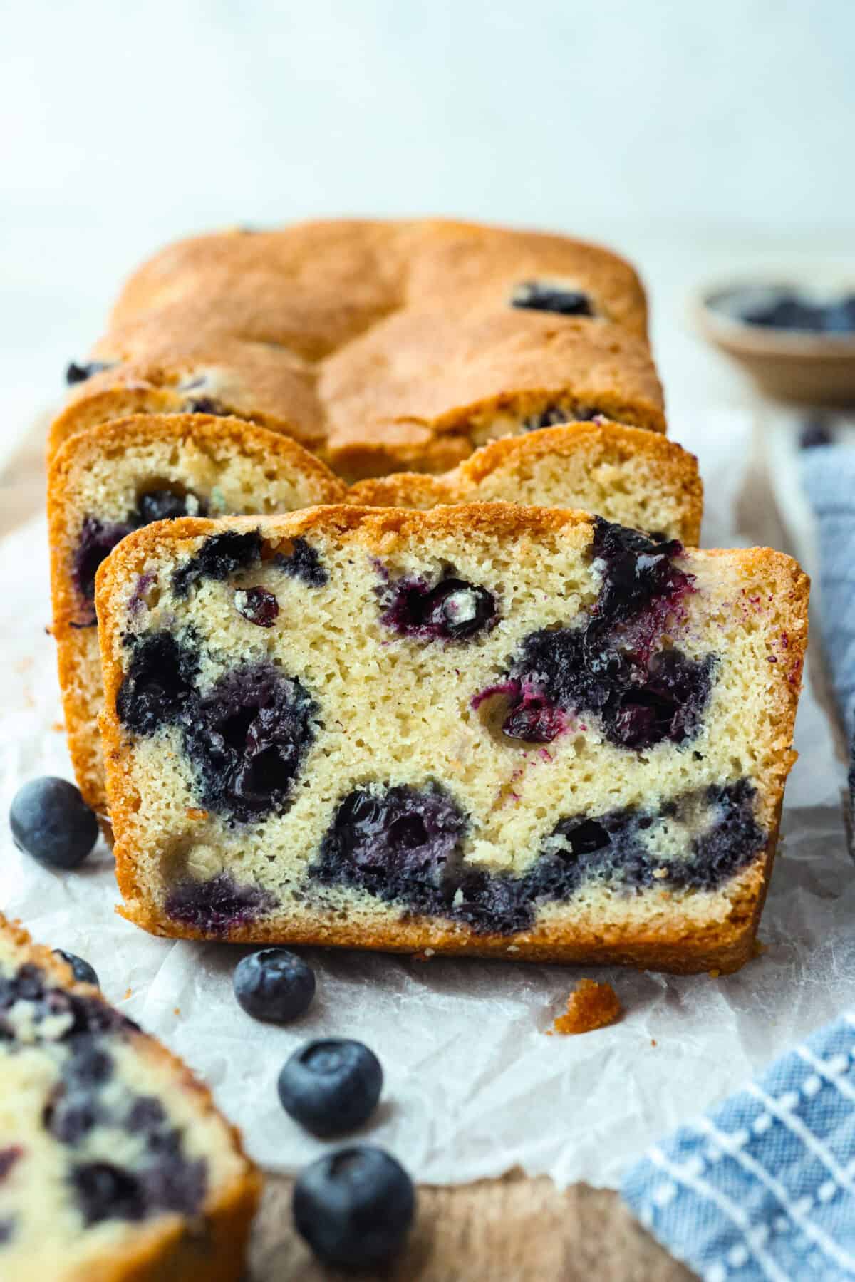 This 5 Ingredient Blueberry Bread is the little shortcut loaf youโll make once and then suddenly need every weekend. Itโs soft, sweet, full of juicy blueberries, and comes together with only five simple ingredients. Side view of 5 ingredient blueberry bread with 2 cut slices.