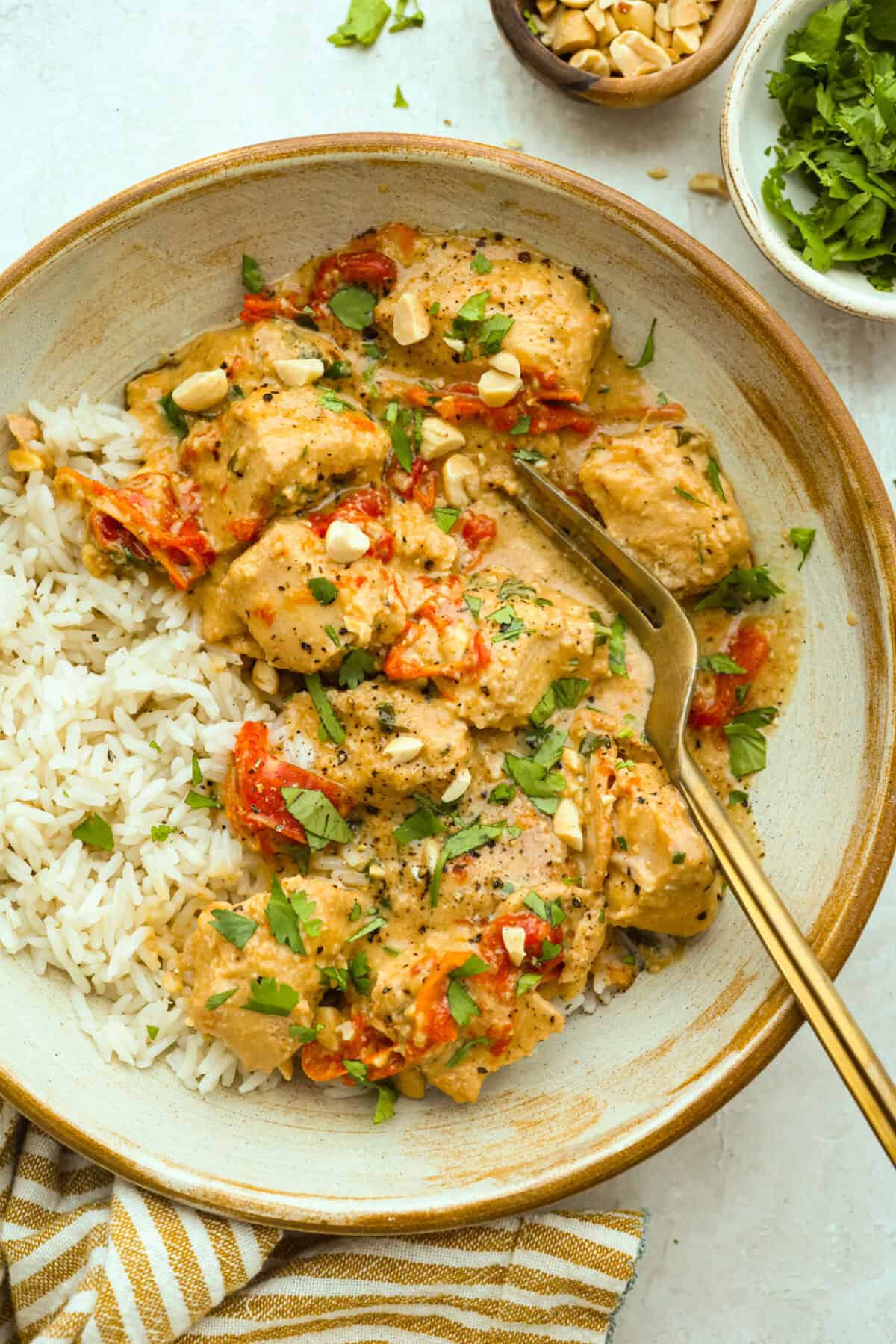 You asked, I listened! This slow cooker Thai peanut chicken got a serious glow-up! The sauce is creamy, savory, a little sweet, and packed with peanut coconut flavor. Iโd drink it with a straw if that were socially acceptable, but spooning it over rice, noodles or adding it to lettuce wraps is probably the better dinner move. Plate of slow cooker Thai peanut chicken over a bed of rice.