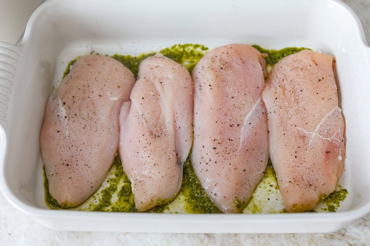 This pesto chicken is the kind of dinner you can assemble right in the baking dish and let the oven take it from there. Add the chicken, pesto, mozzarella, and tomatoes to one pan, bake until tender and bubbly, and dinner is done. Chicken breasts added to the top of the pesto.