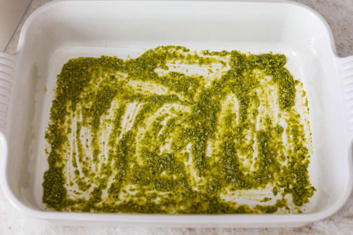 Pesto spread across the bottom of the baking dish.