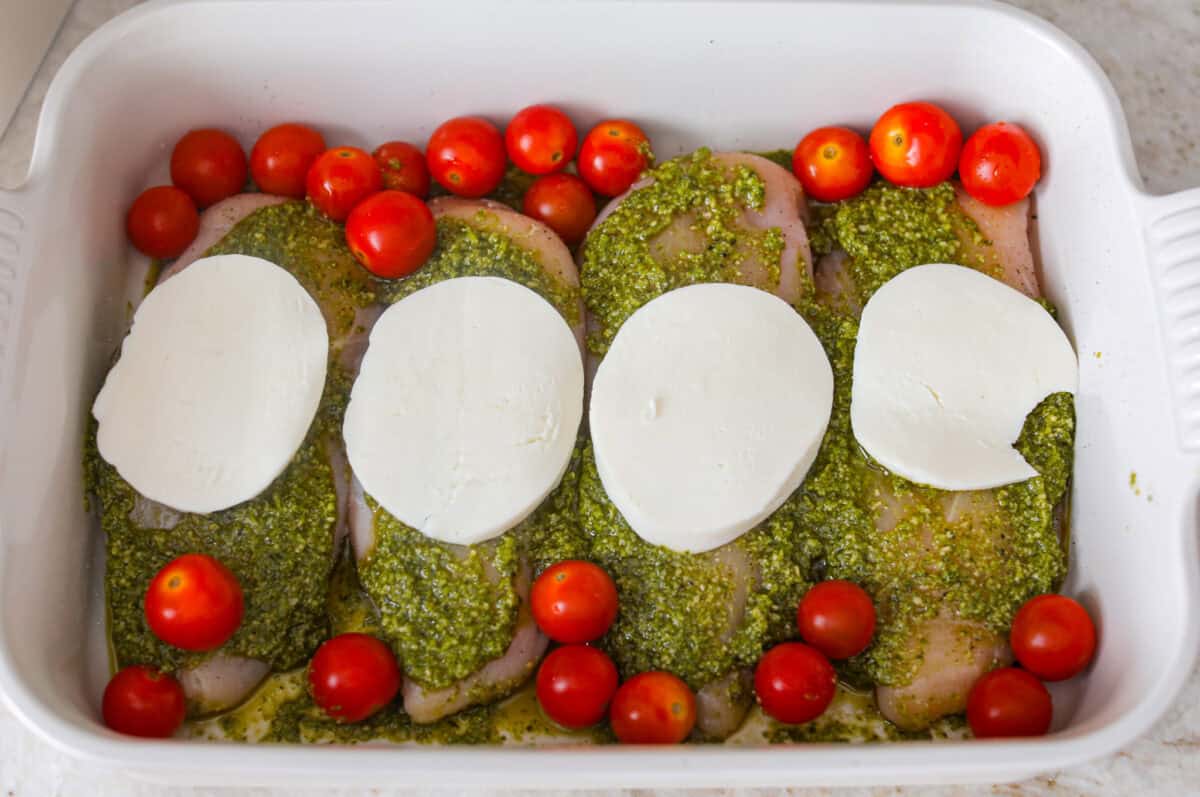 This pesto chicken is the kind of dinner you can assemble right in the baking dish and let the oven take it from there. Add the chicken, pesto, mozzarella, and tomatoes to one pan, bake until tender and bubbly, and dinner is done. Mozzarella cheese and tomatoes added