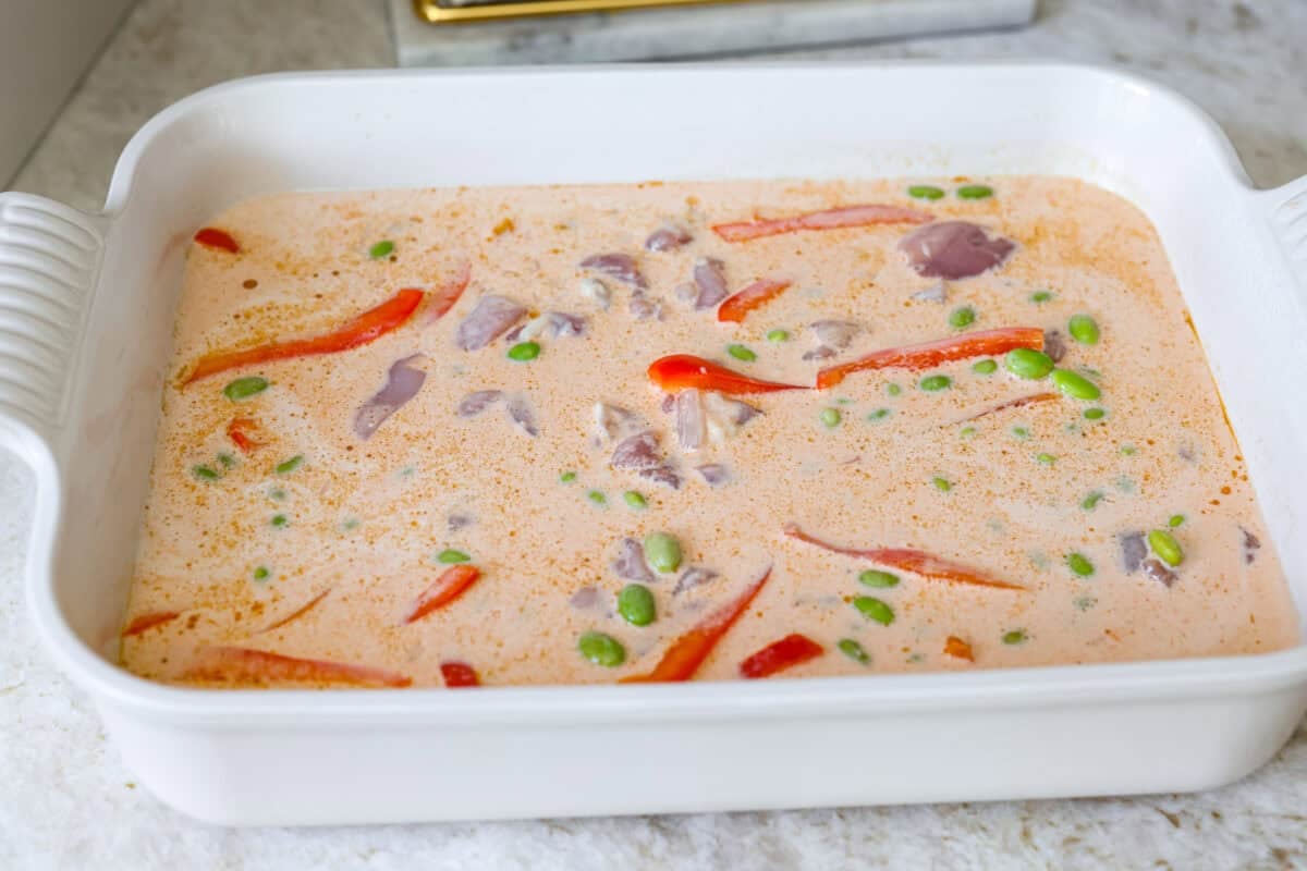 My coconut curry chicken bake proves one pan can do it all! Rice, chicken, and veggies bake in a creamy red curry coconut sauce, soaking up bold Thai flavor. Just 10 minutes of prep, then the oven takes over. All of the ingredients mixed together in the baking dish.
