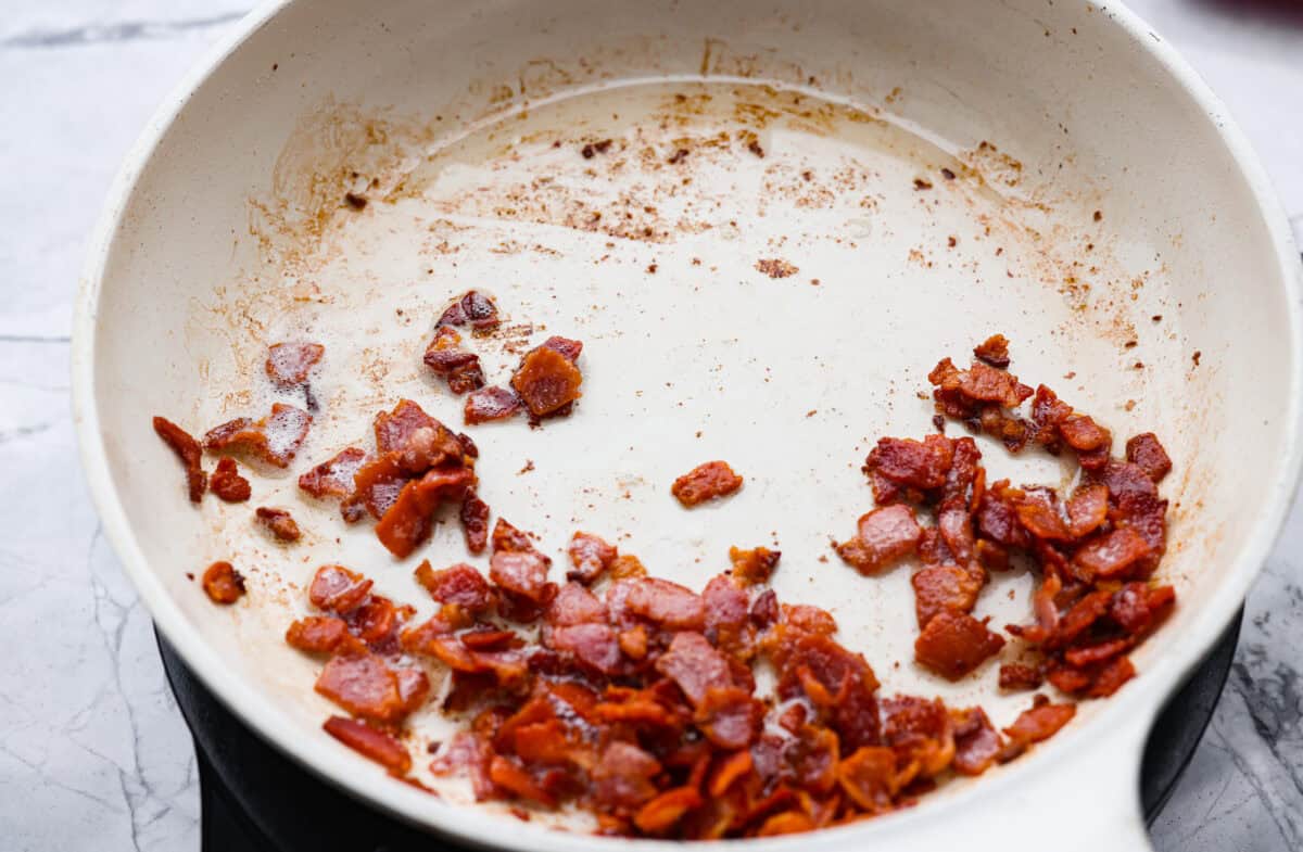 You're going to want this Copycat Grandma Brown’s Famous Baked Beans recipe in your life! It’s sweet, smoky, simple, and the perfect side dish for BBQs, summer cookouts, and every family get together. Bacon cooking in a skillet.