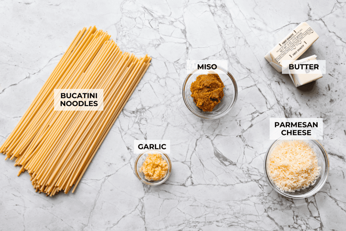 My 5-ingredient miso pasta turns pantry staples into something you'd swear came from a restaurant kitchen. Butter, garlic, and miso melt together into a rich, savory sauce that clings to every strand of bucatini. Overhead shot of labeled ingredients.