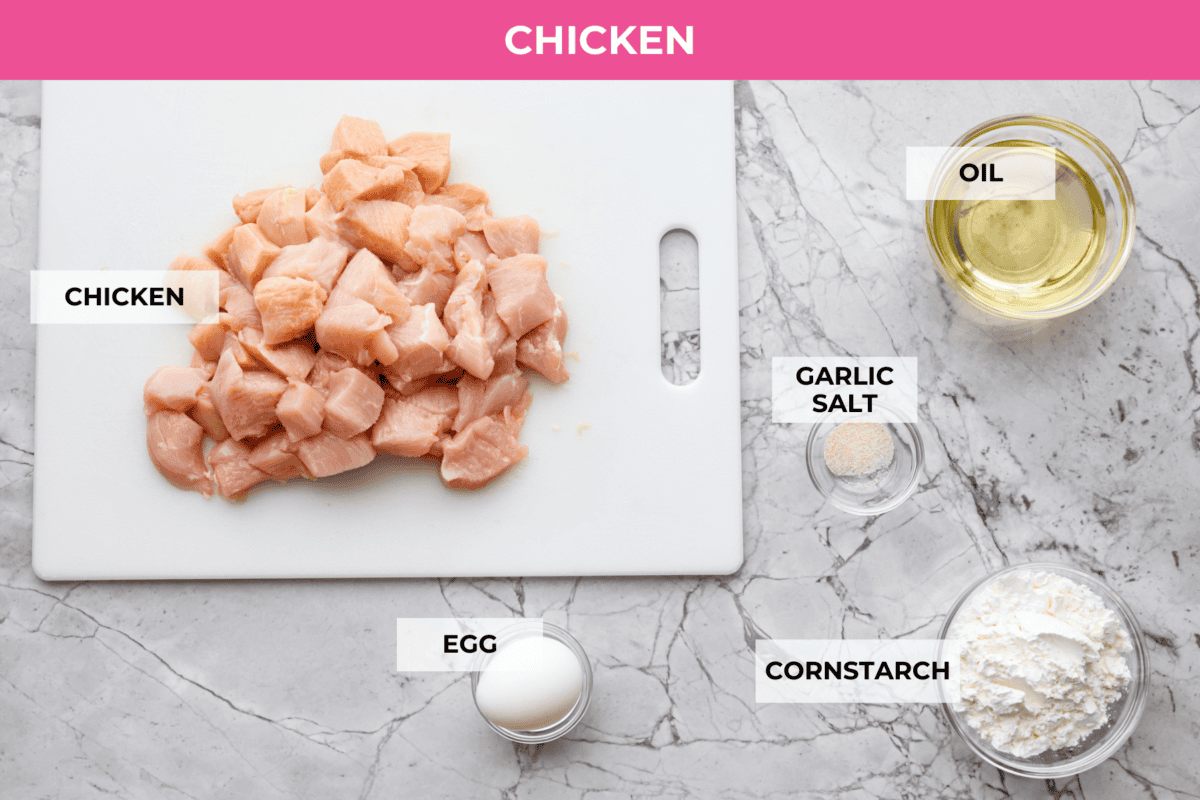 Sticky apricot chicken is crispy, saucy, and loaded with sweet and savory flavor. Golden chicken pieces are tossed in a glossy apricot sauce with garlic, ginger, soy sauce, and a touch of chili paste. Ready in just 30 minutes! Overhead shot of labeled sticky apricot chicken ingredients.