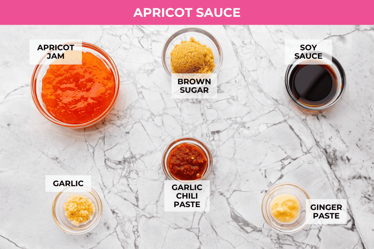 Sticky apricot chicken is crispy, saucy, and loaded with sweet and savory flavor. Golden chicken pieces are tossed in a glossy apricot sauce with garlic, ginger, soy sauce, and a touch of chili paste. Ready in just 30 minutes! Overhead shot of labeled sauce ingredients.
