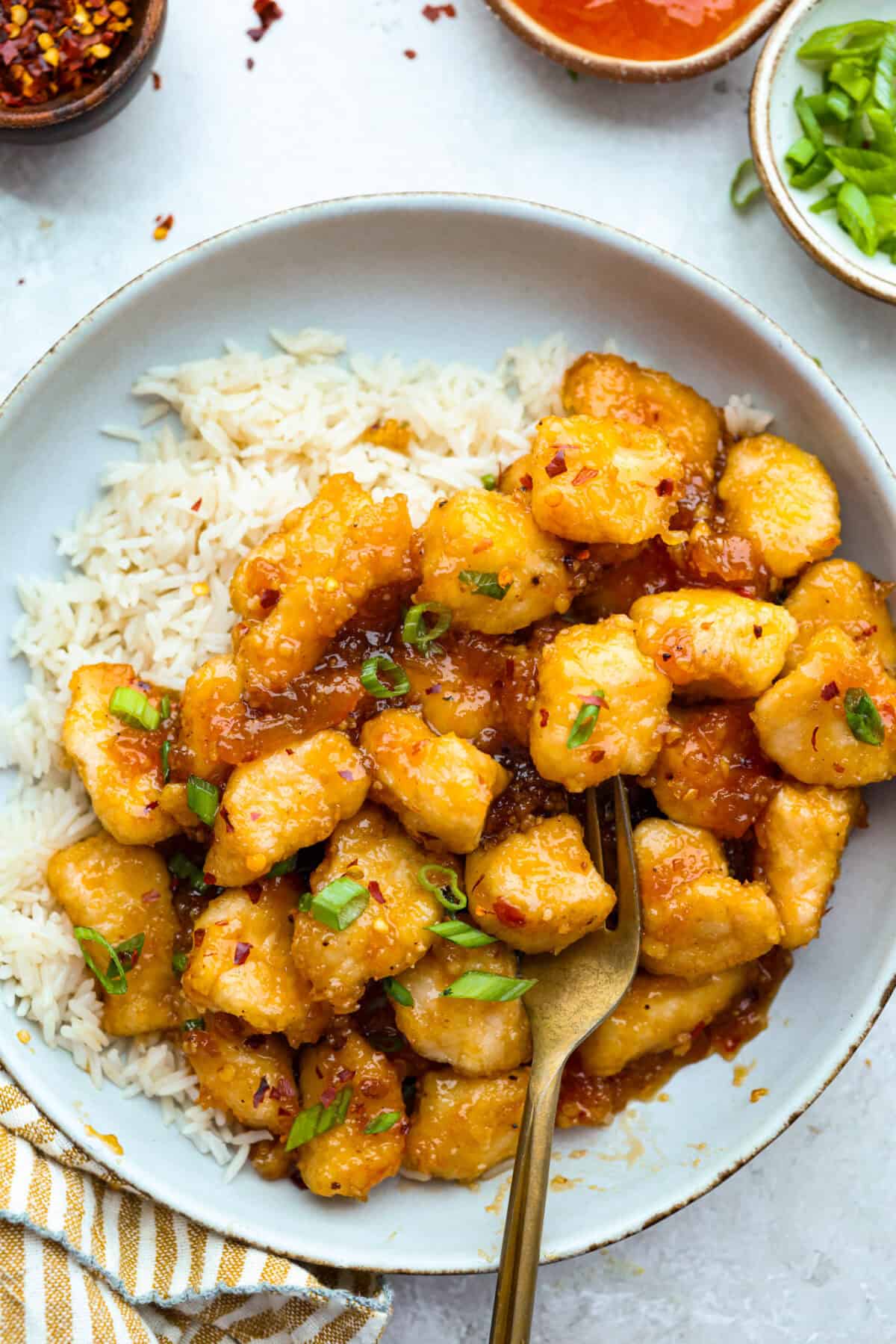 Sticky apricot chicken is crispy, saucy, and loaded with sweet and savory flavor. Golden chicken pieces are tossed in a glossy apricot sauce with garlic, ginger, soy sauce, and a touch of chili paste. Ready in just 30 minutes! Plated sticky apricot chicken on a bed or rice.