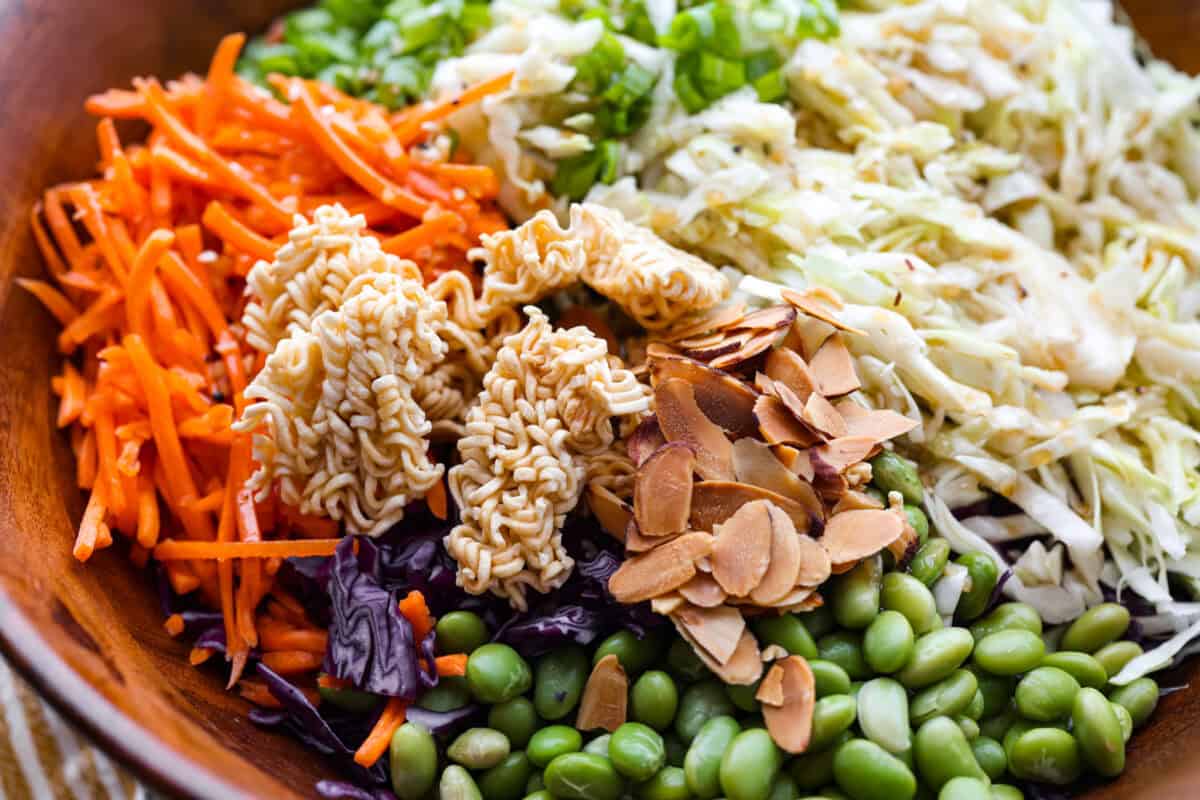 Asian ramen salad is colorful, crunchy, and packed with fresh flavor! It’s made with crisp cabbage, vegetables, toasted ramen noodles, almonds, and a sweet and savory homemade dressing. Toasted noodles and almonds added to the bowl.