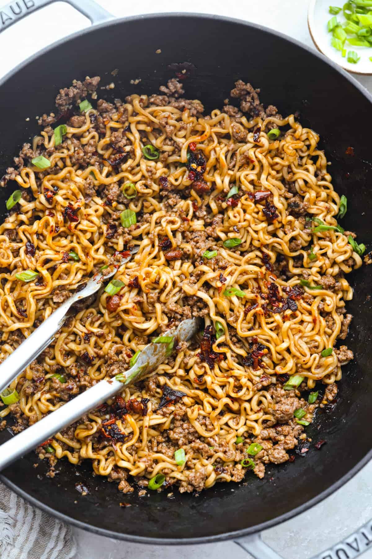 Chili crisp beef ramen noodles are an easy, one-pan dinner you can have on the table in just 20 minutes. Ground beef and ramen noodles cook together in a sweet, savory, and slightly spicy sauce for a quick, filling, and flavorful meal. Skillet filled with chili crisp beef ramen.