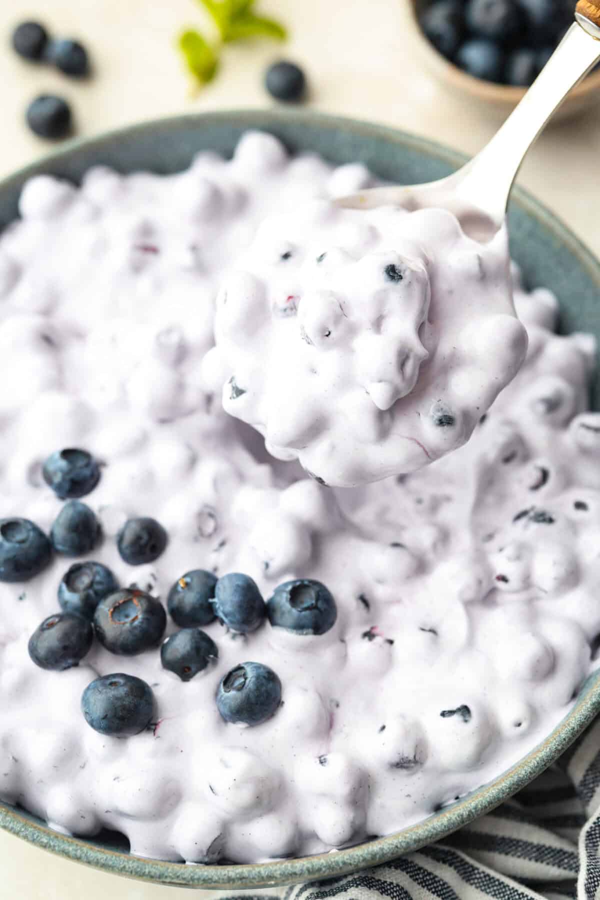 Close up of someone lifting up a serving sized spoonful of blueberry fluff.