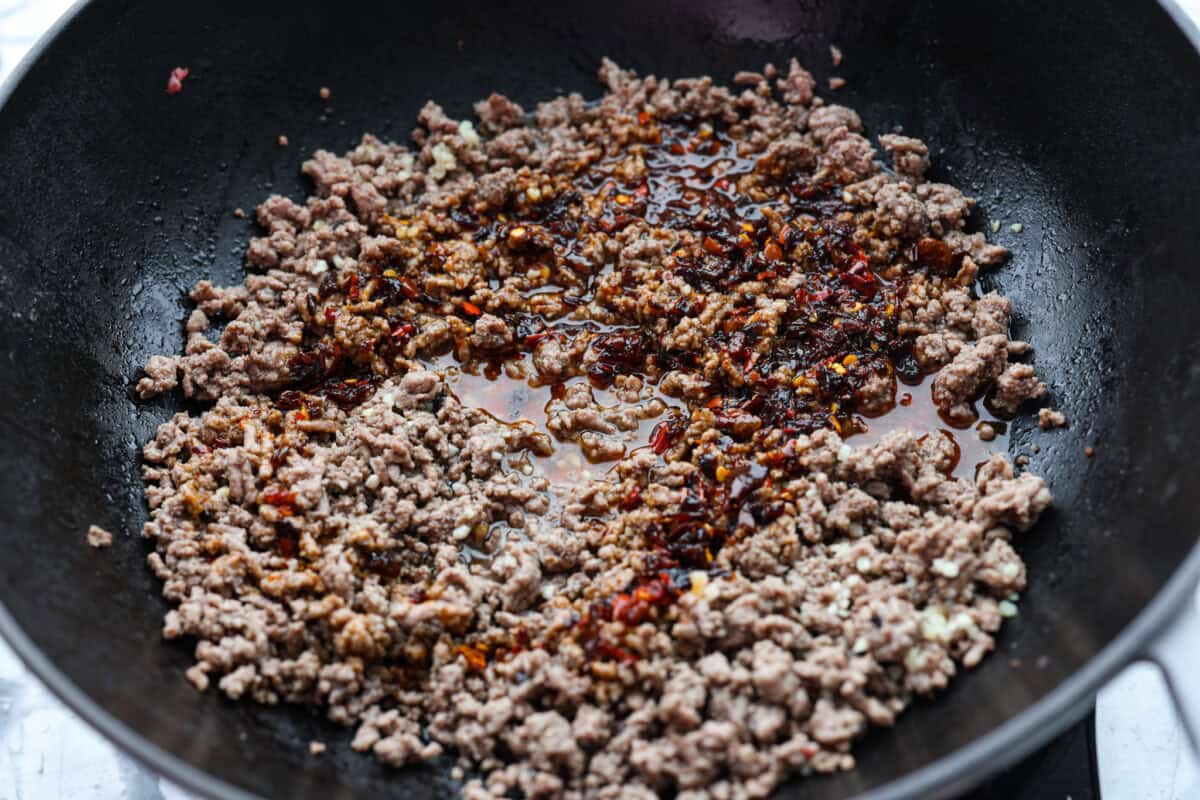 Chili crisp beef ramen noodles are an easy, one-pan dinner you can have on the table in just 20 minutes. Ground beef and ramen noodles cook together in a sweet, savory, and slightly spicy sauce for a quick, filling, and flavorful meal. Sauce added to the ground beef in the skillet.