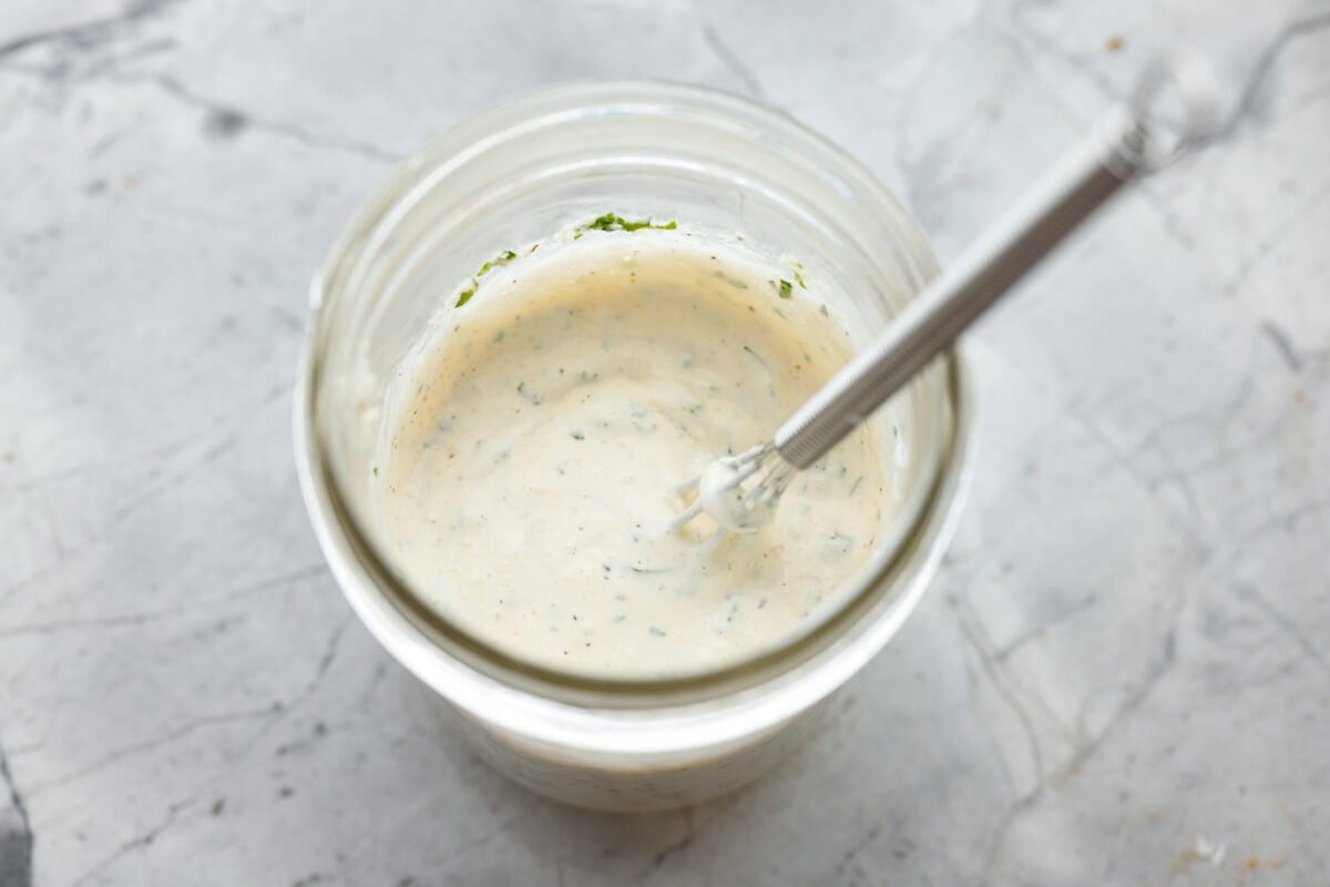 Dressing ingredients whisked together in a small glass container. 