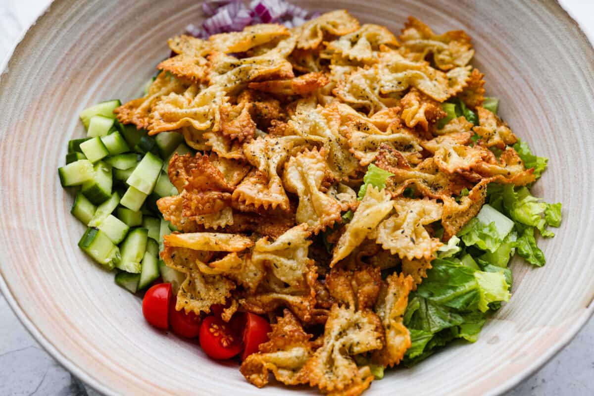 Salad ingredients added to a large serving bowl. 