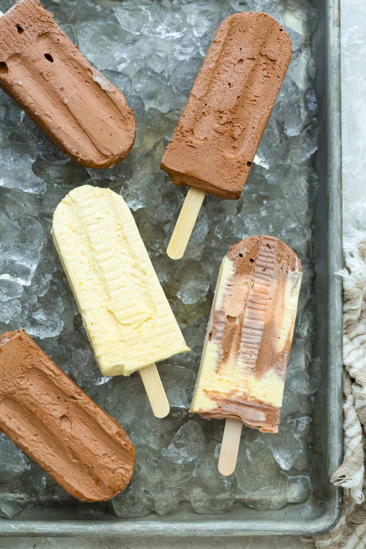 Top down image of pudding pops on a cookie sheet covered in ice t o keep them cold. 