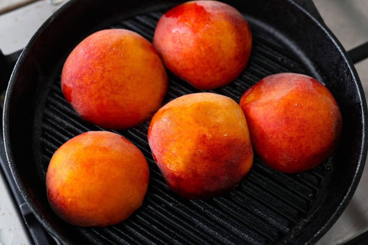 Grilled peaches are one of my favorite ways to turn ripe summer fruit into an easy dessert. The grill brings out their natural sweetness and adds just a little smoky flavor. Serve them warm with vanilla ice cream for a simple treat that feels extra special. Peaches grilling on a grill pan.