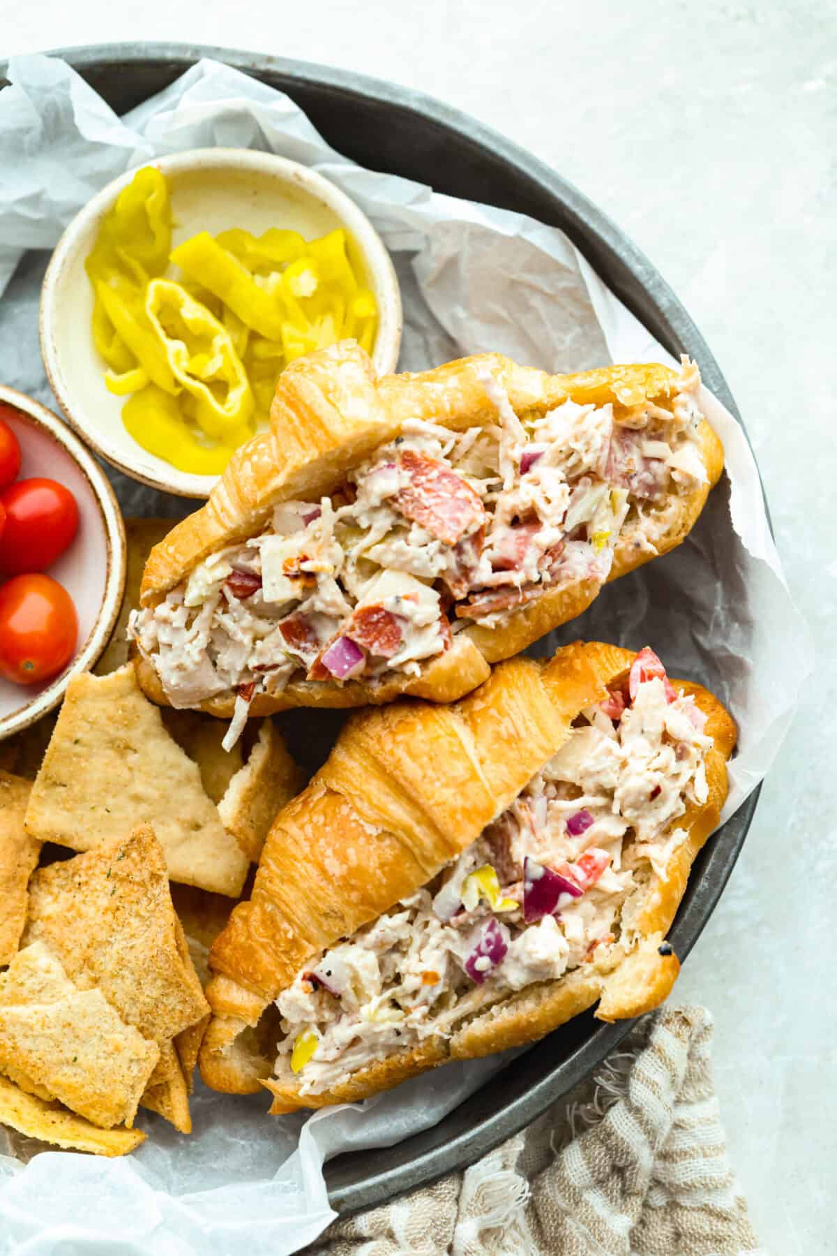 I know you guys love my famous grinder sliders. This grinder chicken salad brings all those bold flavors into one easy recipe. It's hearty, creamy, and perfect for lettuce wraps or a quick lunch straight from the bowl. Platter of grinder chicken salad sandwiches next to pita chips and banana peppers.