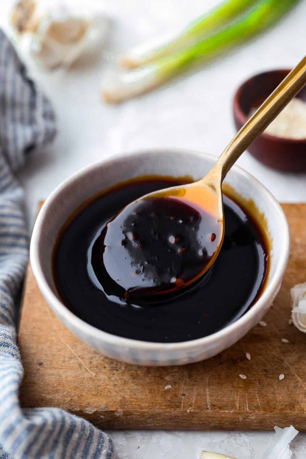 Homemade teriyaki sauce is sweet, savory, and ready in just 10 minutes! It has the perfect thick, glossy texture and tastes incredible on chicken, salmon, vegetables, rice bowls, and more. Small bowl of teriyaki sauce with gold spoon.