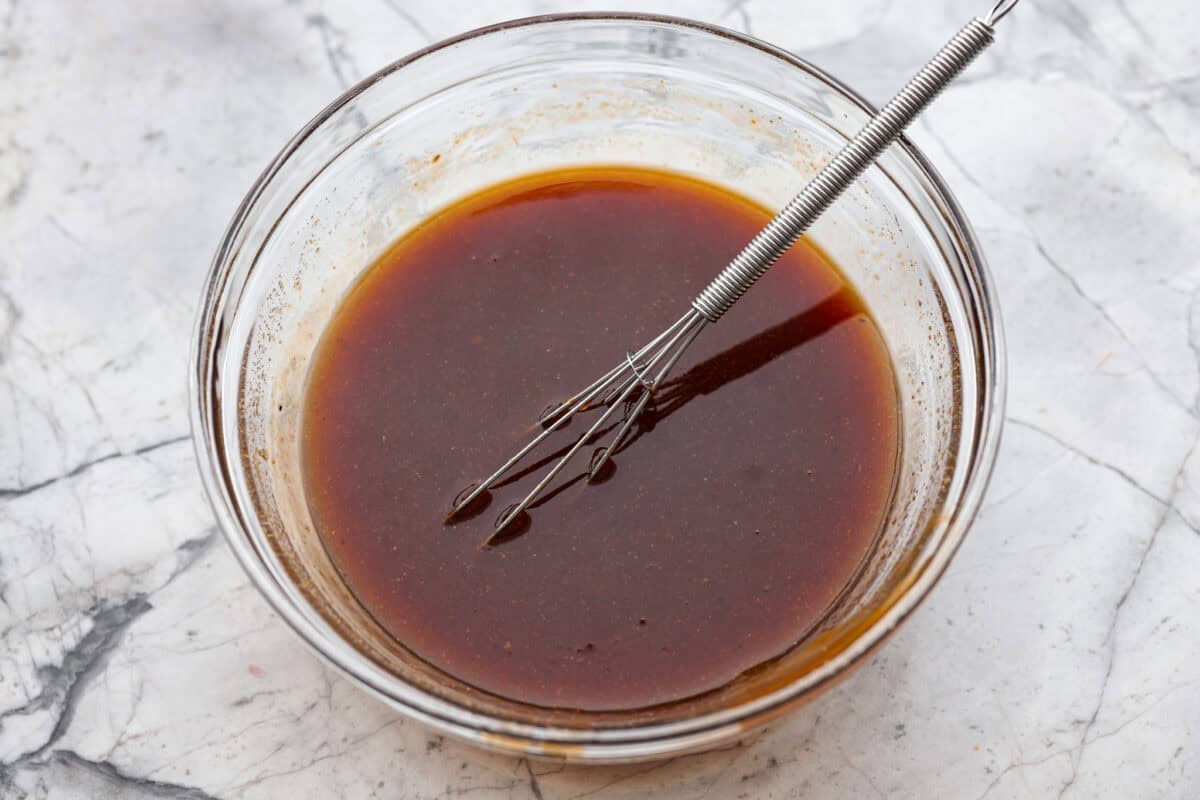 Slow cooker Aloha chicken is sweet, smoky, and so easy to throw together! Tender chicken cooks with pineapple, onion, and barbecue sauce until it’s full of flavor and ready to shred. Serve it over rice for a simple dinner the whole family will love. Slow cooker Aloha chicken sauce ingredients whisked together in a bowl.