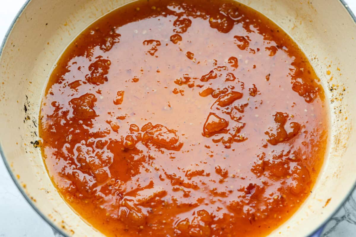 Sticky apricot chicken is crispy, saucy, and loaded with sweet and savory flavor. Golden chicken pieces are tossed in a glossy apricot sauce with garlic, ginger, soy sauce, and a touch of chili paste. Ready in just 30 minutes! Sauce ingredients cooking and thickening in the skillet.
