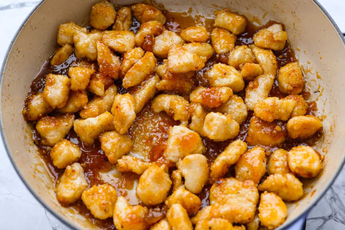 Sticky apricot chicken is crispy, saucy, and loaded with sweet and savory flavor. Golden chicken pieces are tossed in a glossy apricot sauce with garlic, ginger, soy sauce, and a touch of chili paste. Ready in just 30 minutes! Chicken pieces added to the skillet with the apricot sauce.