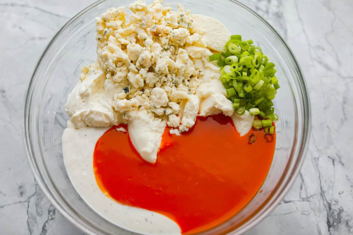 Take your lasagna night to the next level with this buffalo chicken lasagna! Every layer is packed with creamy buffalo sauce, tender shredded chicken, and plenty of melty cheese for a fun twist on a comfort food classic. Sauce ingredients added to a bowl.