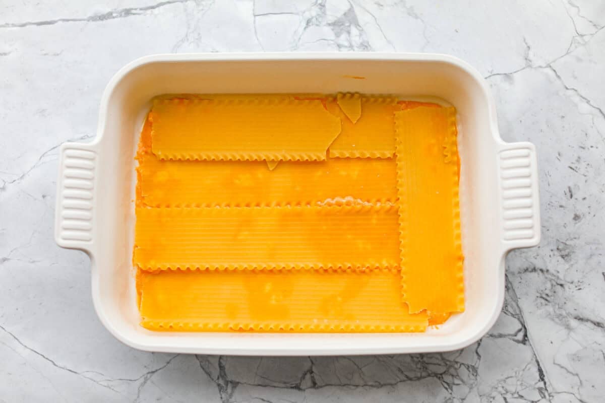 Take your lasagna night to the next level with this buffalo chicken lasagna! Every layer is packed with creamy buffalo sauce, tender shredded chicken, and plenty of melty cheese for a fun twist on a comfort food classic. Oven ready lasagna noodles spread out over the buffalo sauce mixture.