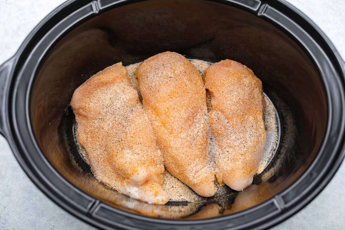 This crockpot chicken spaghetti will have everyone running to the dinner table! The slow cooker does the work while the chicken becomes tender and flavorful, then it's tossed with spaghetti, melty cheese, and a creamy sauce. Chicken breasts seasoned in. the bottom of the crockpot.