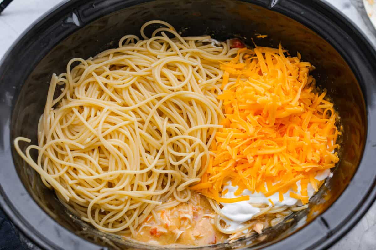 This crockpot chicken spaghetti will have everyone running to the dinner table! The slow cooker does the work while the chicken becomes tender and flavorful, then it's tossed with spaghetti, melty cheese, and a creamy sauce. Cooked spaghetti noodles, cheese and sour cream added to the chicken and sauce mixture.