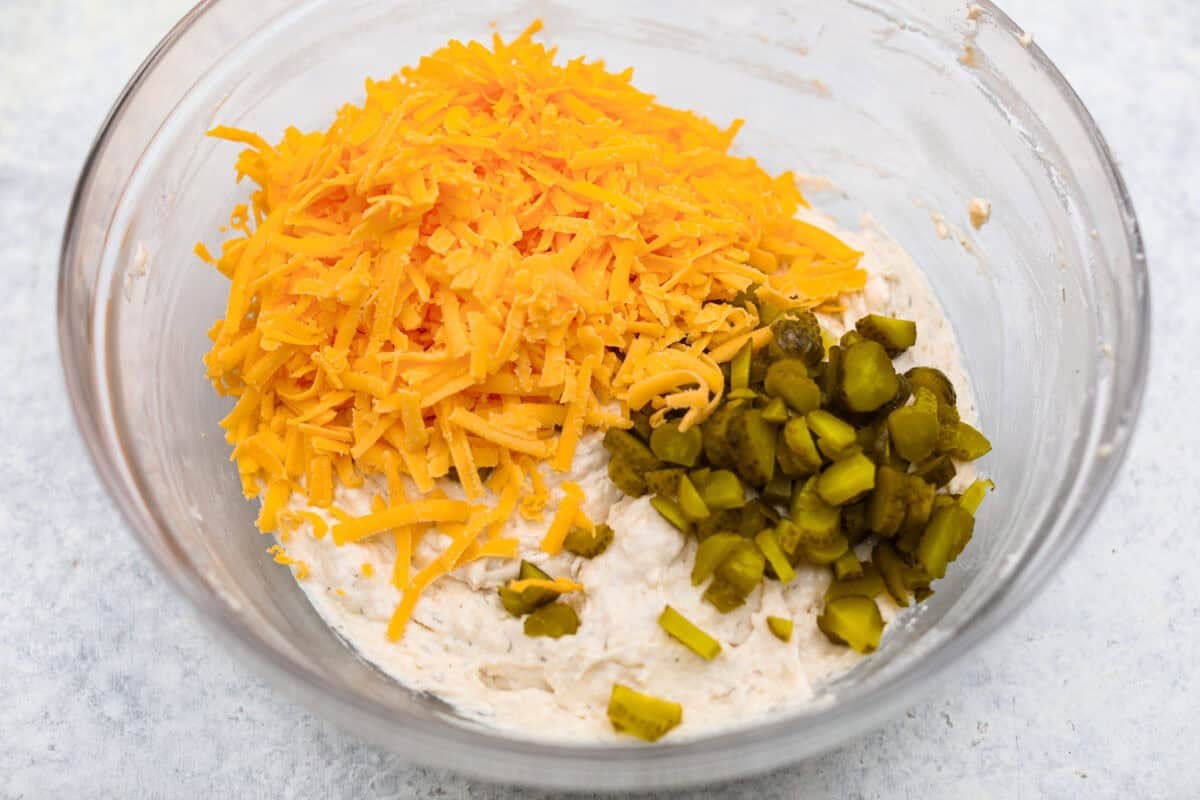 Dill pickle bread is cheesy, buttery, and packed with tangy pickle flavor in every bite. Chopped dill pickles and my secret dill pickle seasoning give this easy quick bread even more bold, briny flavor, with plenty of melty cheese. Cheese and pickles added to the dough.