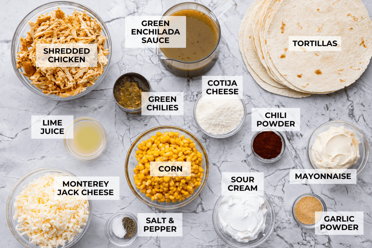 These street corn chicken enchiladas are creamy, cheesy, and packed with zesty flavor. An easy 40-minute dinner the whole family will love. Overhead shot of labeled ingredients.
