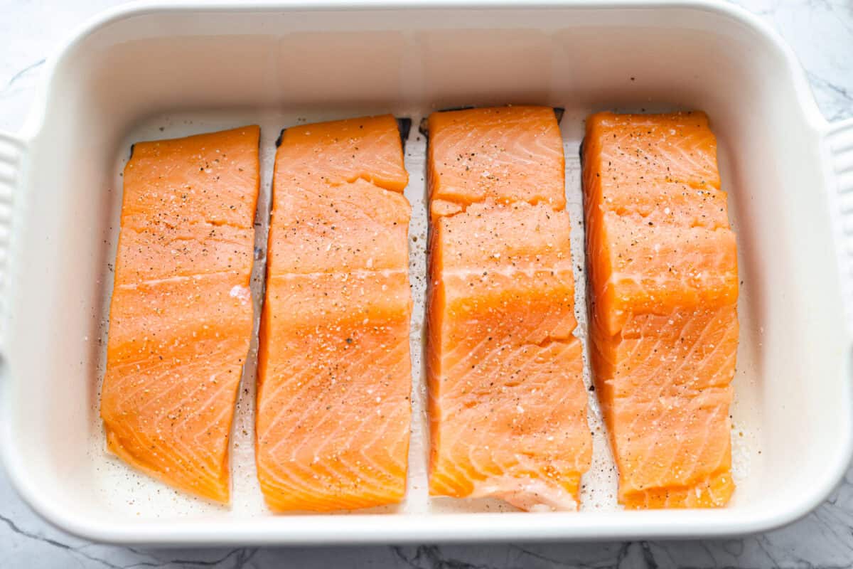 Maple glazed salmon has that perfect sweet-and-savory flavor that keeps you going back for just one more bite. As it bakes, the maple glaze turns glossy and caramelized while the salmon stays buttery, flaky, and melt-in-your-mouth tender. Seasoned salmon filets in a baking dish.