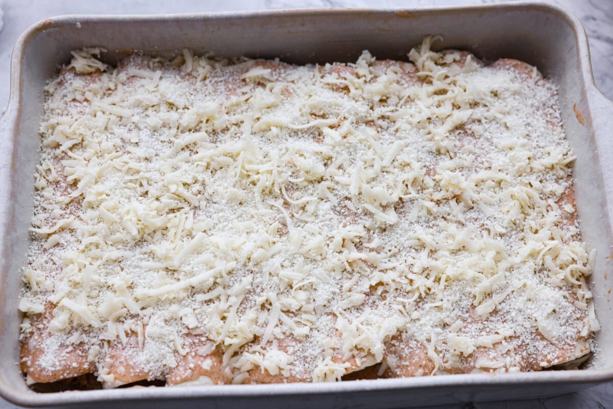 These street corn chicken enchiladas are creamy, cheesy, and packed with zesty flavor. An easy 40-minute dinner the whole family will love. Filled tortillas covered with sauce and cheese ready to go in the oven.