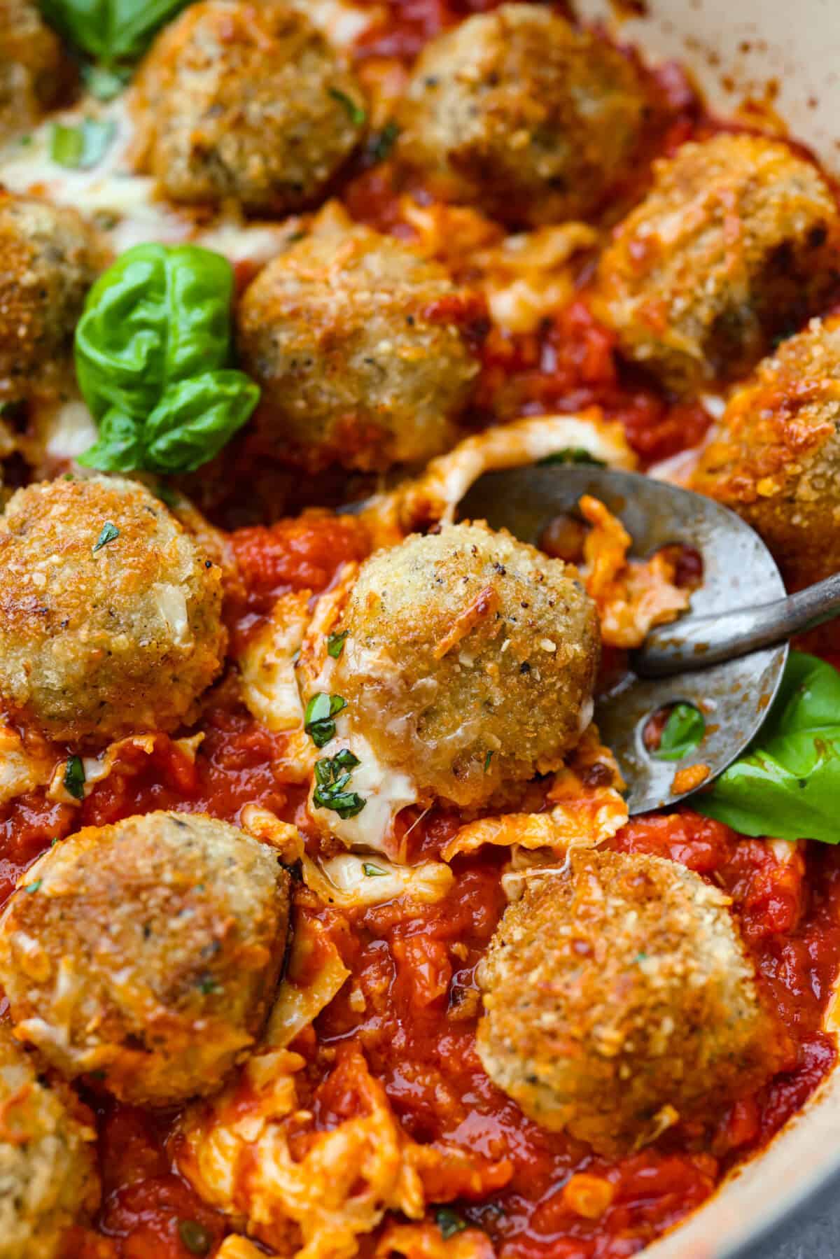 Chicken parmesan meatballs bring all the best parts of chicken parmesan together in one skillet. Think tender chicken meatballs, crispy Parmesan breadcrumbs, saucy marinara, and lots of melted mozzarella. Close up picture of the chicken parmesan meatballs all browned and baked and ready to eat.