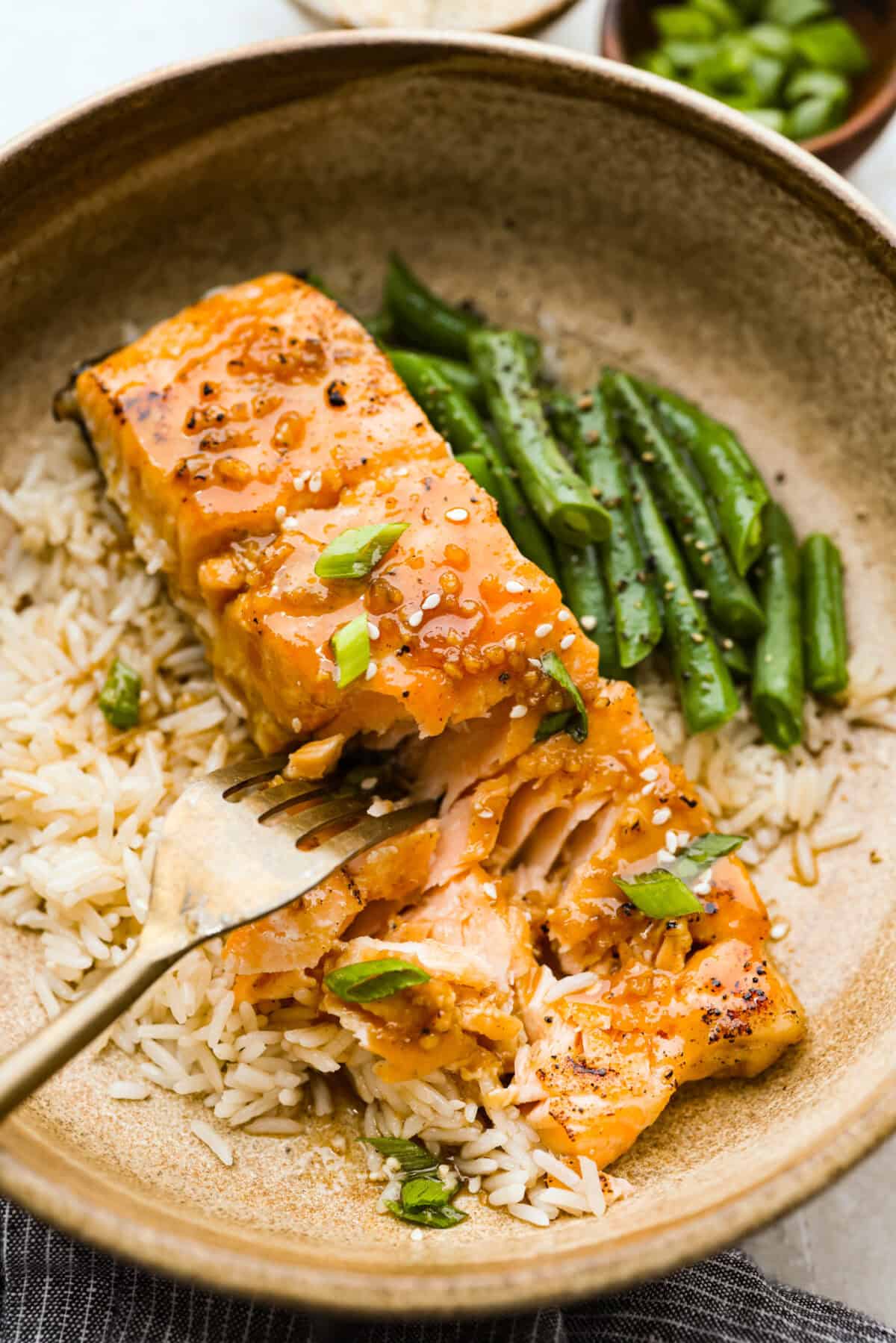 Maple glazed salmon has that perfect sweet-and-savory flavor that keeps you going back for just one more bite. As it bakes, the maple glaze turns glossy and caramelized while the salmon stays buttery, flaky, and melt-in-your-mouth tender. Plated maple glazed salmon on a bed of white rice and a side of green beans.