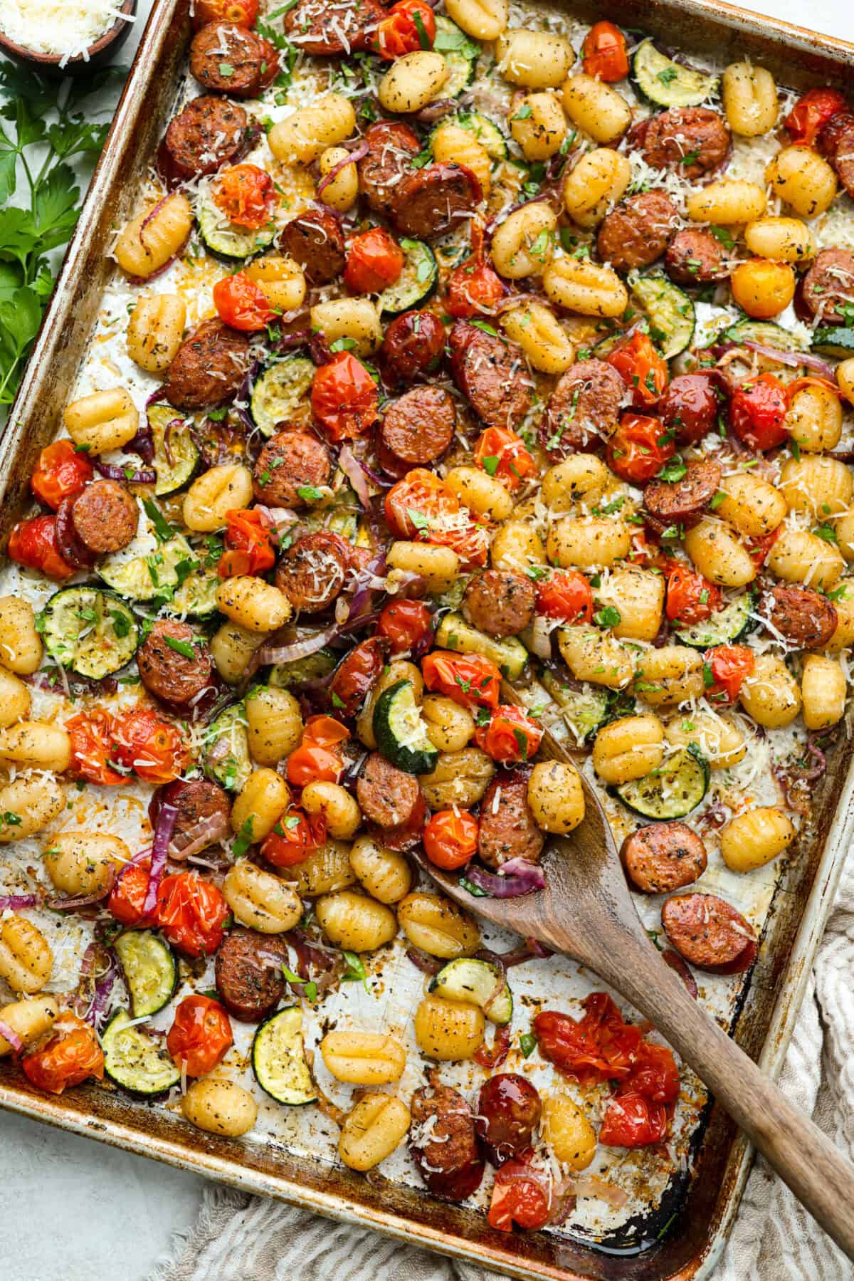 This sheet pan gnocchi is about as easy as dinner gets! Everything goes onto one pan with olive oil and Italian seasoning, then roasts until the gnocchi is crispy and the veggies are tender. Finish it with Parmesan and dig in! Sheet pan gnocchi cooked and toped with parmesan cheese and parsley.