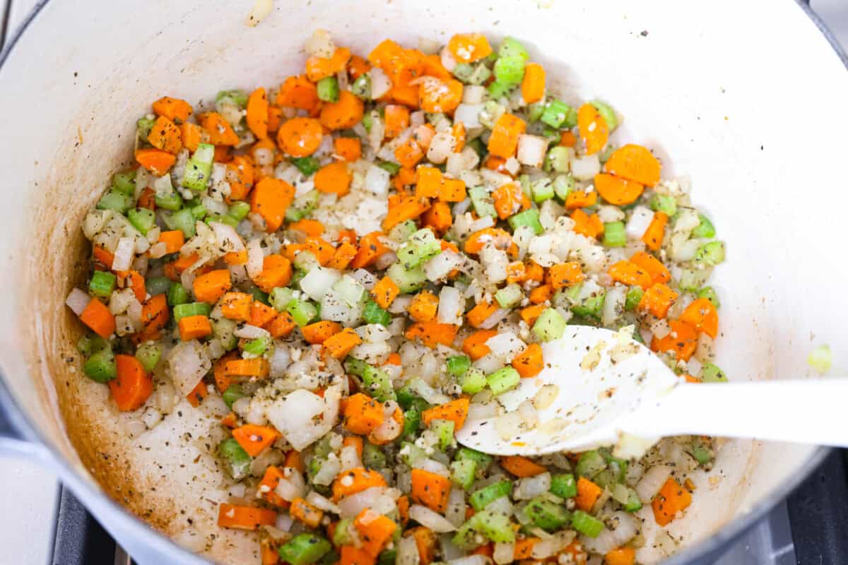 Chicken and dumpling soup will have everyone racing to the table! This one-pot dinner is loaded with tender chicken, hearty vegetables, and a creamy broth. Soft homemade dumplings steam right on top for the perfect finishing touch. Seasonings and garlic added to the pot with flour.